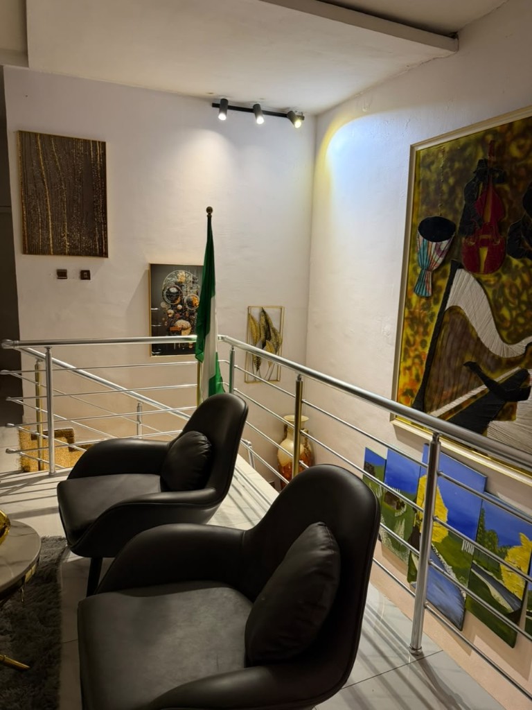 Landing with black chairs, the Nigerian flag, and a large painting.