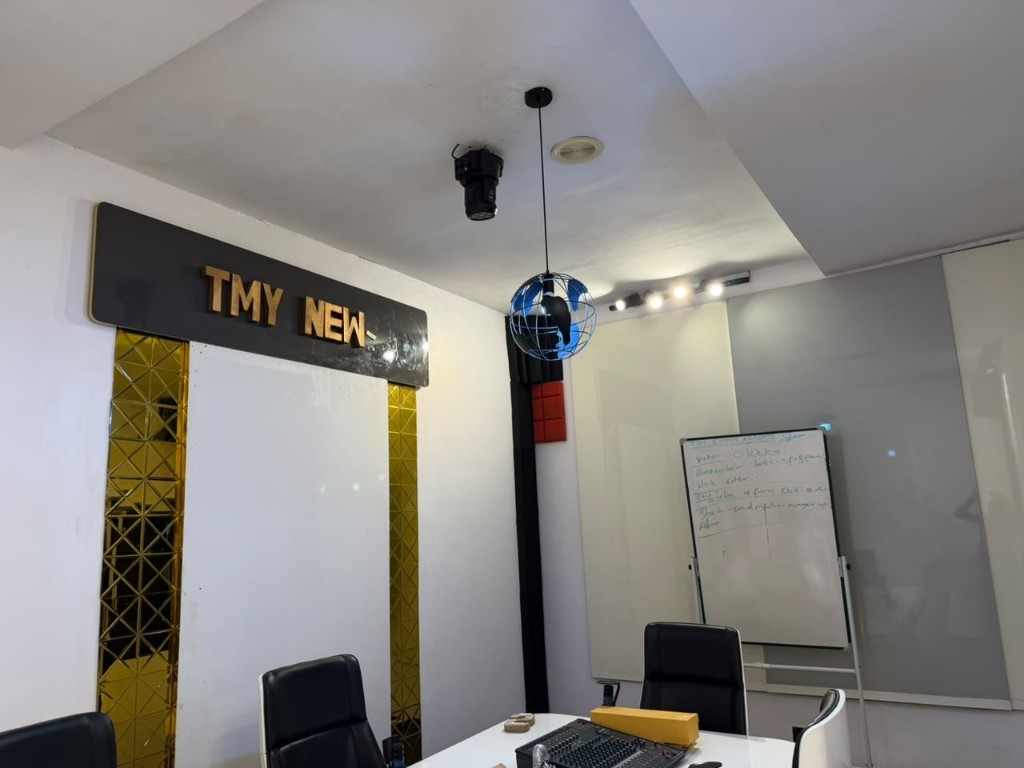 Newsroom doorway under a TMY News sign, with gold mirror panels.