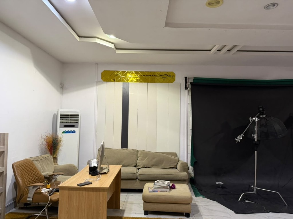 Photo studio with a sofa, a desk, and a black backdrop.