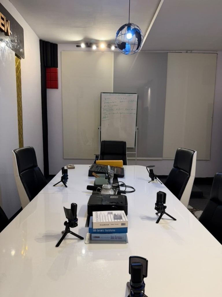 Microphones, a mixer, and books laid down the podcast table.