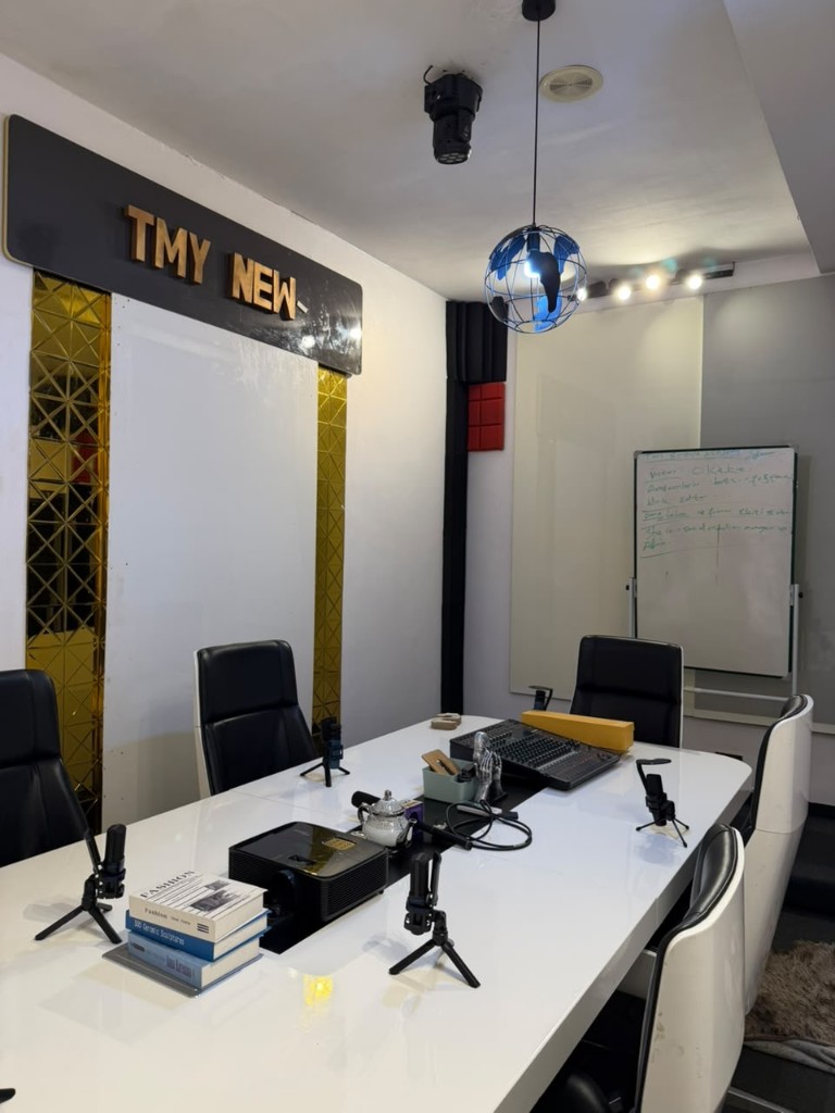 Podcast room: a white table, mixer, and the TMY News sign.